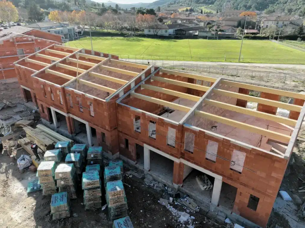 Bâtiment en briques avec charpente en bois, chantier en cours.