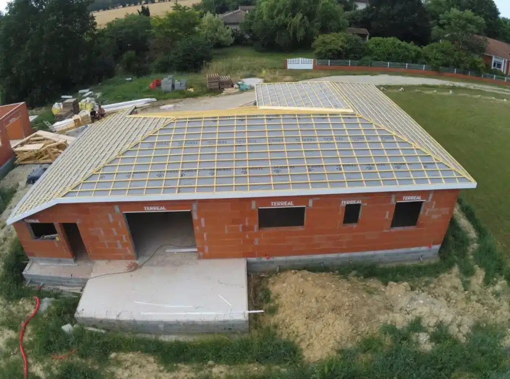 Vue aérienne de la toiture partiellement lattée d'une maison en construction."